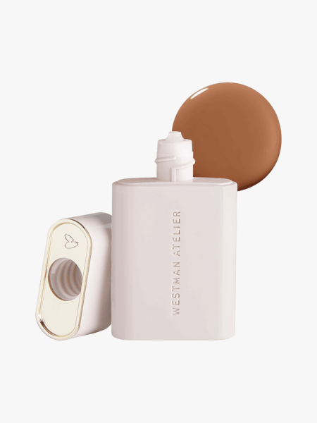Westman Atelier Vital Skincare Complexion Drops in branded pale pink bottle with gold and white cap atop product swatch on light gray background
